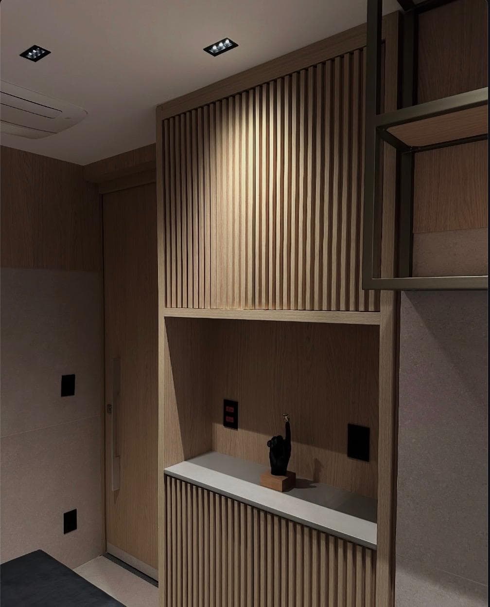 An entry hall unit in slatted oak with a recessed stone shelf, lit from above.