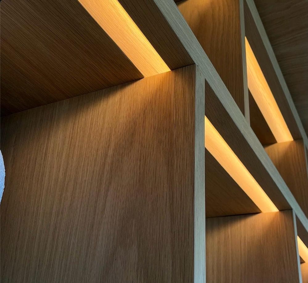 A close view of oak shelving with LED strips concealed in the underside of each shelf.